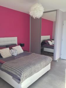 sypialnia z różowymi ścianami, łóżkiem i lustrem w obiekcie La chambre rose w mieście Mâcon