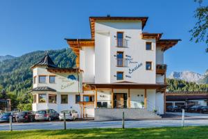 a large white building with cars parked in a parking lot at Hotel Enzian in Pertisau
