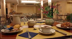 a table with plates of food and a cup of coffee at Hotel Ghibellino in Buonconvento