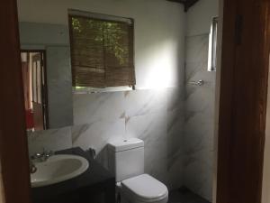 een badkamer met een toilet, een wastafel en een raam bij Upland Inn in Kandy