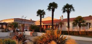 a building with palm trees in front of it at Hotel et Spa Les Cleunes Oléron in Saint-Trojan-les-Bains