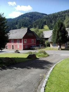 una casa roja al lado de una carretera en La vecchia Mesnerhaus, en Pusterwald