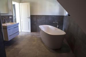 a bathroom with a large tub and a sink at Ferienhaus VINETA Schneckenhus LODDIN in Loddin