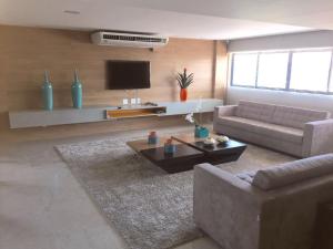 ein Wohnzimmer mit einem Sofa und einem TV in der Unterkunft Apartamento Port Ville Mar Azul in Maceió