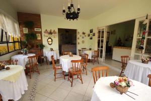 a restaurant with tables and chairs with white table cloth at Pousada Jardim Porto Belo in Porto Belo