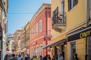 een groep mensen die door een straat met gebouwen lopen bij Leona Deluxe Apartments in Pula