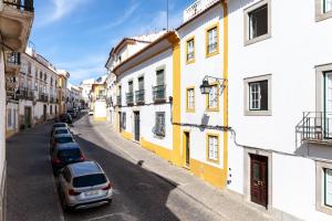 eine Straße mit Autos, die an den Seiten der Gebäude geparkt sind in der Unterkunft Poet's house in historic center in Évora