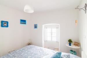 a white bedroom with a bed and a window at Poet's house in historic center in Évora