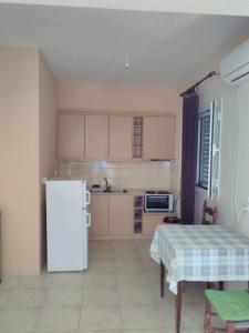 a kitchen with a white refrigerator and a table at Klidonas Apartments in Akrogiali