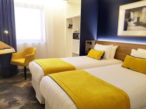 Cette chambre d'hôtel comprend 2 lits avec des draps jaunes. dans l'établissement B&B HOTEL Paris 17 Batignolles, à Paris