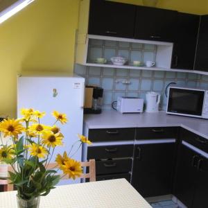 Il comprend une cuisine équipée d'un réfrigérateur blanc et d'une table ornée de fleurs jaunes. dans l'établissement Pipacs apartmanok, à Balatonboglár