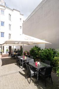 un patio con tavoli, sedie e ombrellone di Hotel Bitburger Hof a Bitburg