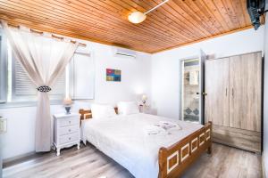 1 dormitorio con cama blanca y techo de madera en Hotel Sofia, en Matala