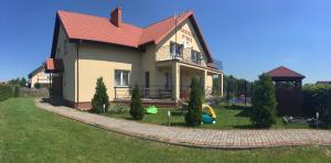 een klein huis met een tuin met een speeltuin bij Pokoje w Słonecznym Domku in Rowy