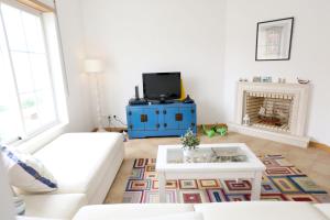 un salon avec un canapé blanc et une télévision dans l'établissement Like-home-T2 Apt-Blue Dreams-sea view, à Ericeira