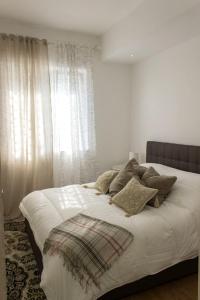a bedroom with a white bed with pillows and a window at L'ULIVO - home suite in Bari