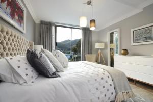 1 dormitorio con cama blanca y ventana grande en dk villas 2 The Boardwalk (Hout Bay) en Hout Bay