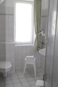 a bathroom with a toilet and a sink and a window at Hotel Haus Kranich in Prerow