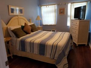 a bedroom with a bed with a striped comforter and a television at Royal North Beach in Clearwater Beach