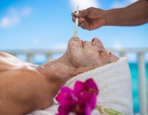 a man laying on the beach with a toothbrush in his mouth at SeaGarden Beach Resort - All Inclusive in Montego Bay