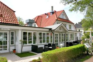 ein Haus mit einem Wintergarten mit schwarzen Stühlen und Fenstern in der Unterkunft Hotel Haus Kranich in Prerow