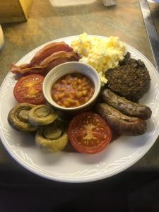 a plate of breakfast food with sausage eggs beans and meat at Dunclutha Guest House in Leven