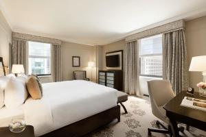 a bedroom with a white bed and a desk andwindows at Fairmont Hotel Vancouver in Vancouver
