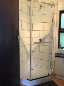 a shower with glass doors in a bathroom at Natures Way Farm Cottage in The Crags
