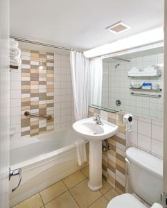a bathroom with a sink, toilet and bathtub at L'Appartement Hôtel in Montreal