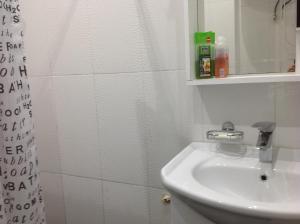 Baño blanco con lavabo y espejo en Comfortable Apartment near the Sea, en Kobuleti
