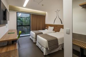 um quarto de hotel com duas camas e uma janela em Linx Galeão no Rio de Janeiro