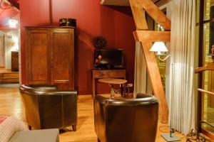 a living room with leather stools and a television at B&B Het Hof van Petronilla in Gooik