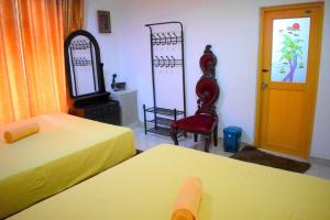 a room with two beds and a chair and a door at Green Heritage Holiday Resort in Mahiyangana