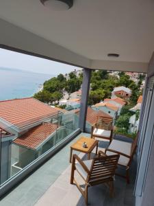 a balcony with chairs and a table and the ocean at Apartmani Marija in Baška Voda