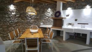 a dining room with a wooden table and a stone wall at Empress Villa in Platis Yialos Mykonos