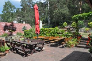 a patio with tables and benches and a red umbrella at Penzion Zuzana in Staré Splavy