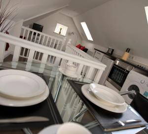 un comedor con platos blancos en una mesa de cristal en Aberdeen Serviced Apartments - The Lodge, en Aberdeen