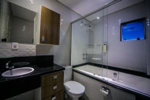 a bathroom with a toilet and a sink and a shower at Hotel Pousada Laguna Rosa in Barra de Ibiraquera