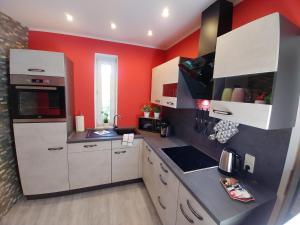 uma cozinha com armários brancos e paredes vermelhas em gapart - Apartments mit Küche em Leipzig