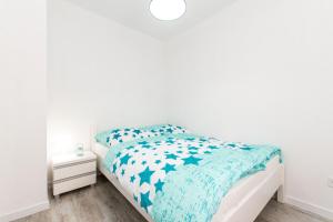 a white bedroom with a bed with a blue comforter at DOMKI NOWĘCIN in Łeba