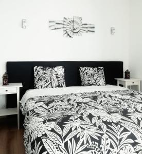 um quarto com uma cama preta e branca com almofadas em Pirata hostel Milfontes em Vila Nova de Milfontes