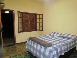 ein Schlafzimmer mit einem Bett mit einer blau-weißen Decke in der Unterkunft Pousada Fazenda Bocaina in Inhaúma