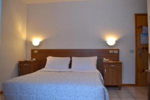 a bedroom with a bed with two lights on the wall at Hotel Pineta in Falcade