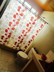 a bathroom with a toilet and a curtain with flowers at Casa Bambú Tropical in Alajuela