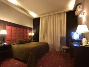 Habitación de hotel con cama, escritorio y TV. en Hotel Doro City, en Tirana