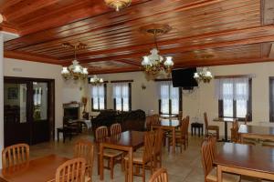 una sala da pranzo con soffitti e tavoli in legno e sedie di Balkoni Zagoriou a Vradeto