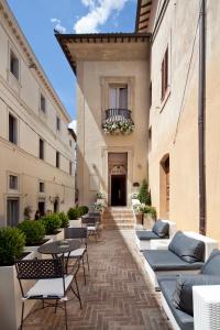 un patio con mesas y sillas en un edificio en Hotel Degli Affreschi, en Montefalco