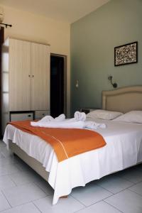 アモピにあるEsperida rooms & studiosのベッドルーム1室(大型ベッド1台、オレンジと白の毛布付)