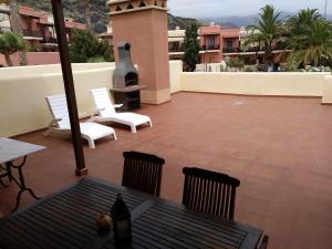 een patio met witte stoelen en een grill op een gebouw bij VV Sweet Tabaiba "by henrypole home" in Los Cancajos