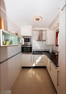 a large kitchen with white cabinets and appliances at Apartment in Playa de las Americas 1 in Playa de las Americas